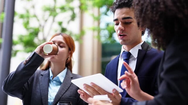 Tablet review between colleagues outdoors, a businessman and an auburn-haired businesswoman weighing options together under office-campus trees on a warm city workday morning