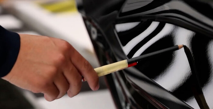 View of a technician marking a paint defect on the glossy black surface of a car body in Hiroshima, Hiroshima, Japan.
