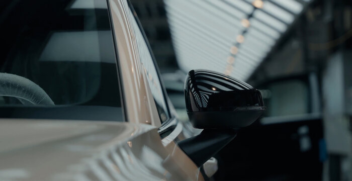 View of a car side mirror in an automotive factory with robotic assembly lines in the background in Hiroshima, Hiroshima, Japan.