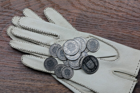 The gloves on the table have a few Swiss franc coins on them
