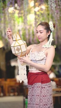 Slow motion of Asian woman in traditional Northern Thai dress holding a Lanna paper lantern.