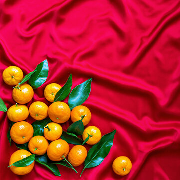 Fresh mandarin oranges with leaves on red silk