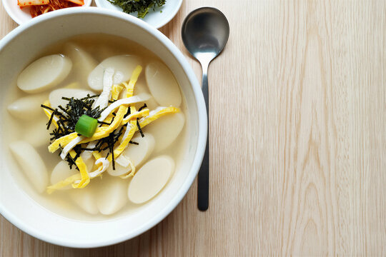Overhead bowl of Korean rice cake soup with egg and seaweed