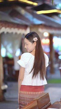 Slow motion of a beautiful Asian woman in traditional Thai attire posing gracefully outdoors.