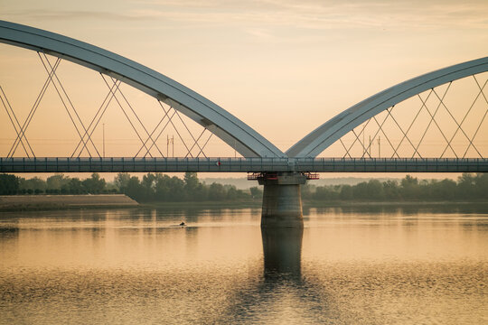 View of the Zezelj Bridge spanning the Danube River during a calm golden hour in Novi Sad, Vojvodina, Serbia.