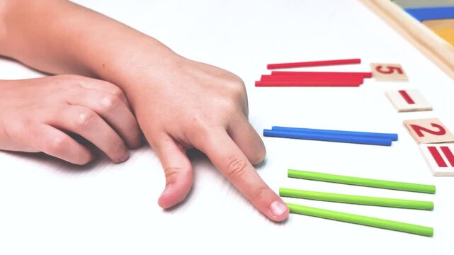 Side view video of child hands counting colorful wooden sticks with finger on table Preschool Educational learning game for fine motor skills development with copy space Montessori sensorial activity