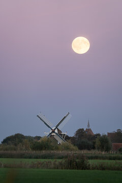 Full moon over a traditional windmill in the Dutch countryside. Groningen, the Netherlands.