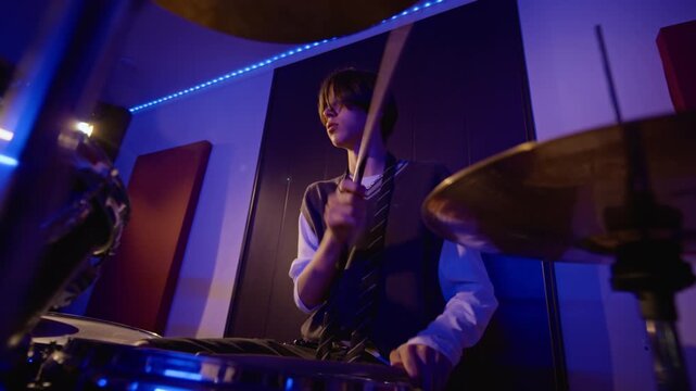 Caucasian teenage boy passionately playing drum kit during rehearsal. Perfect for music education campaigns, youth lifestyle branding, band promotions, or creative arts content