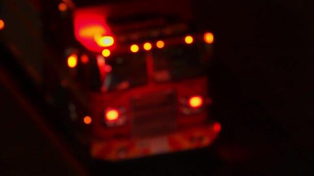 Fire truck first responders with flashing emergency lights at night fire accident scene. Blurry fire truck with glowing lights responding and arrive to emergency call alert. Emergency siren flashing.