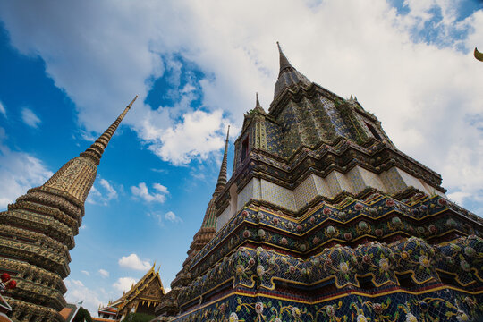 View of the ornate stupas at Wat Phra Chetuphon Wimon Mangkhalaram Rajwaramahawihan against a blue sky in Krung Thep Maha Nakho, Thailand.