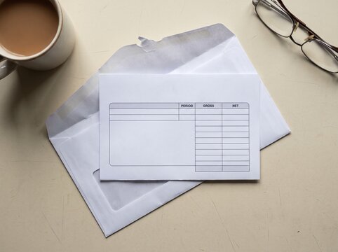 Blank Pay Slip Form In Open Envelope With Coffee And Glasses