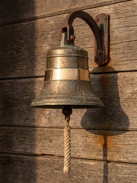 Brass Ship Bell With Blank Polished Band On Weathered Wooden Wall