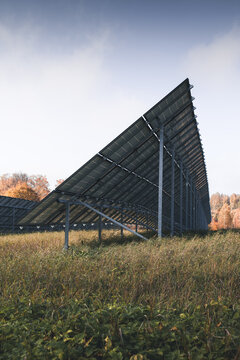 View of solar panels installed in a grassy field with autumn trees in the background under a clear sky in Otepaa, Valga County, Estonia.