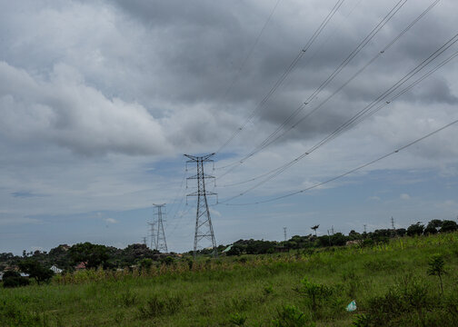 View of electricity transmission towers standing in a grassy landscape under a cloudy sky in Jos, Plateau, Nigeria.