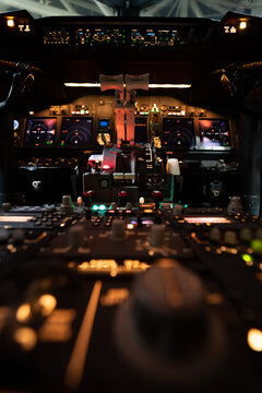 View of the illuminated cockpit of a Boeing 737-800 at Hannover Airport with glowing flight instrument panels and throttle controls in Langenhagen, Niedersachsen, Germany.