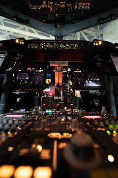 View of the illuminated cockpit of a Boeing 737-800 at Hannover Airport with glowing instrument panels and navigation displays in Langenhagen, Niedersachsen, Germany.