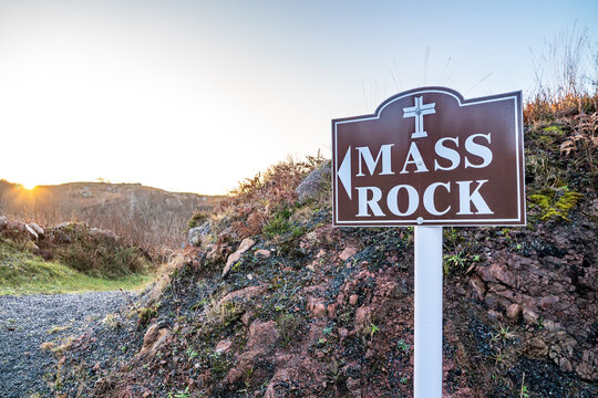 View of the Kincasslagh Mass Rock signpost set against a rocky hillside during the golden hour in Kincasslagh, County Donegal, Ireland.