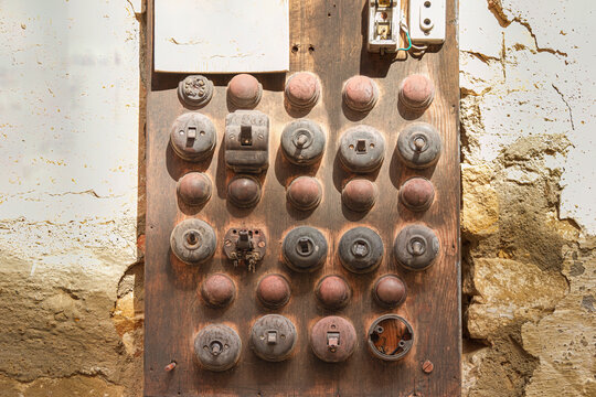 Panel el&eacute;ctrico antiguo con fusibles de cer&aacute;mica sobre madera envejecida, s&iacute;mbolo del pasado industrial y la evoluci&oacute;n tecnol&oacute;gica en la historia de la electricidad y la ingenier&iacute;a