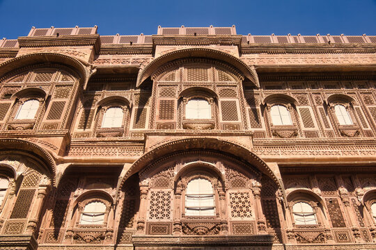 View of the intricate sandstone carvings and arched windows of the historic Mehrangarh Fort in Jodhpur, Rajasthan, India.