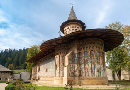 View of the historic Voronet Monastery featuring intricate exterior frescoes and traditional architecture in Voronet, Judetul Suceava, Romania.
