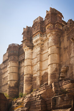 View of Mehrangarh Fort featuring intricate Rajput architecture and massive sandstone walls rising above rocky terrain in Jodhpur, Rajasthan, India.