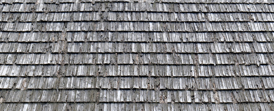 Weathered grey wooden roof shingles texture, old aged timber shakes overlapping rows full frame, rustic barn roof surface background, natural wood grain pattern, panoramic closeup detail
