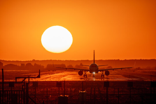 View of an airplane on the runway at Bucharest Henri Coanda International Airport during a vibrant sunset in Otopeni, Judetul Ilfov, Romania.