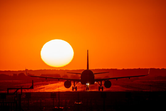 View of a commercial airplane silhouette on the runway at sunset at Bucharest Henri Coanda International Airport in Otopeni, Judetul Ilfov, Romania.