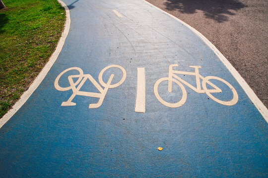 View of a blue painted bicycle lane with white bicycle symbols on the asphalt in Helsinki, Uusimaa, Finland.