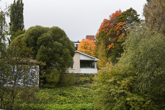 View of a house nestled among vibrant autumn trees with orange and yellow foliage in a residential area of Jyvaskyla, Central Finland, Finland.