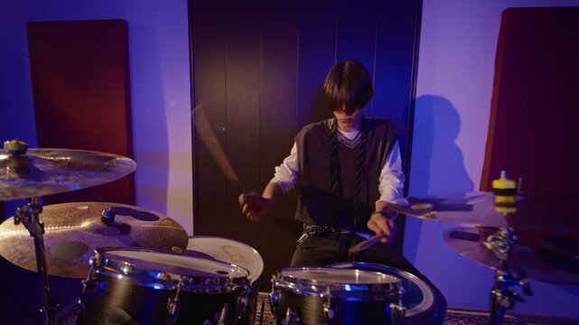 Caucasian teenage boy playing drum kit with drumsticks during music rehearsal session. Footage perfect for youth education, entertainment campaigns or artistic lifestyle media