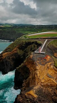 Remote Azorean lighthouse on a rocky cliff above rough Atlantic ocean on Sao Miguel Island, Azores