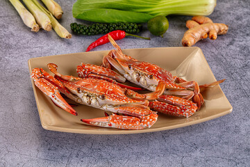 Seafood dish featuring two cooked red crabs with white speckles on beige plate surrounded by lemongrass lime chili and turmeric for Asian cuisine © Andrei Starostin