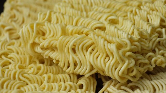 Macro texture of raw instant ramen noodles slowly rotating.