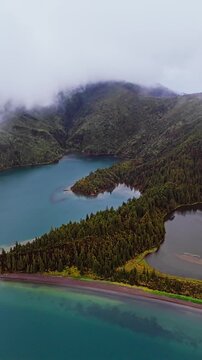 Crater lake in Azores with layered water tones and volcanic terrain. Lagoa do Fogo aerial view with low visibility clouds