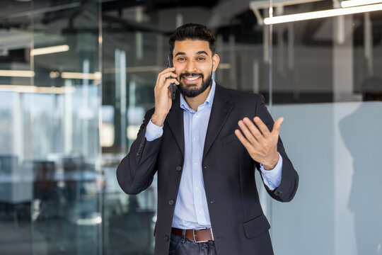 Young indian businessman talking on phone in modern office