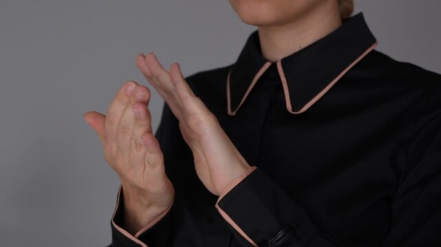 Young business woman claps her hands, showing appreciation, approval, and positive emotion in a professional business setting with a neat elegant look