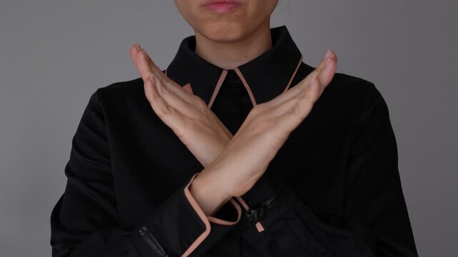 Young business woman shows a strict gesture of disagreement, crossing her hands to say no, expressing refusal, disapproval, and strong business boundaries