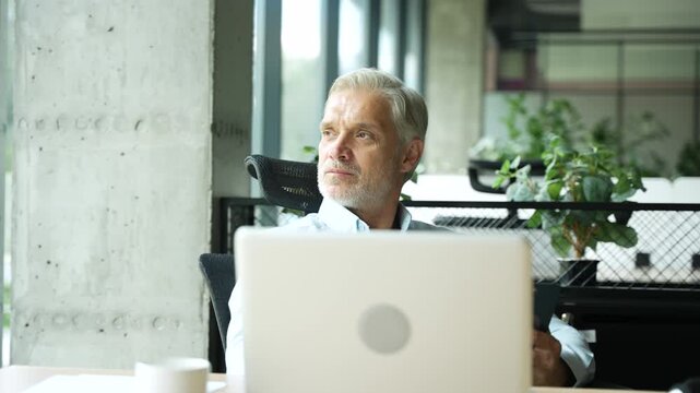 Mature 40s focused businessman, executive director working using laptop, doing data base online research sitting at office. Successful business man, leader, ceo manager, trader trading crypto currency