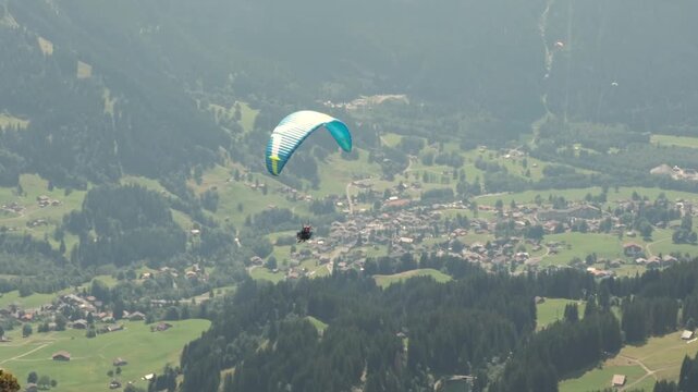 Tandem paragliding flight over Grindelwald near First mountain, Switzerland. Professional pilot and passenger flying above scenic alpine landscape. Concept of adventure tourism, outdoor recreation.