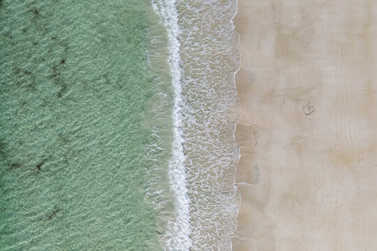 Aerial top view abstract tropical island shore. Tranquil turquoise ocean lagoon soft sandy beach sunlit. Minimalist relaxing nature travel background. Luxury destination vacation wall art wallpaper
