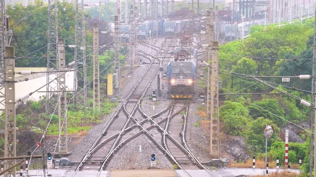 Elevated View of Electric Freight Train Approaching on Multiple Railway Tracks with Overhead Wires
