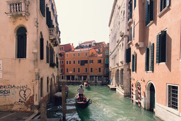Gondolas move through a narrow Venetian canal bordered by weathered pastel buildings. © Dillon T.