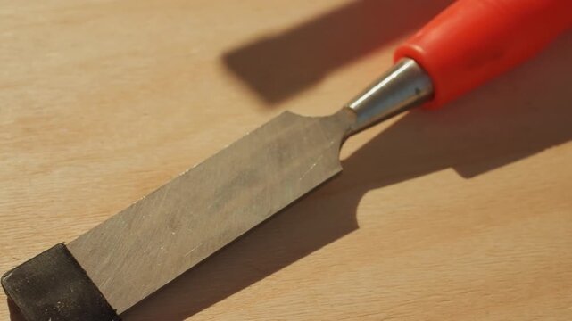 Close up shots show chisels with metal blades resting on light wood. focus is steady throughout highlighting texture of both wooden background and metallic tool surfaces without movement