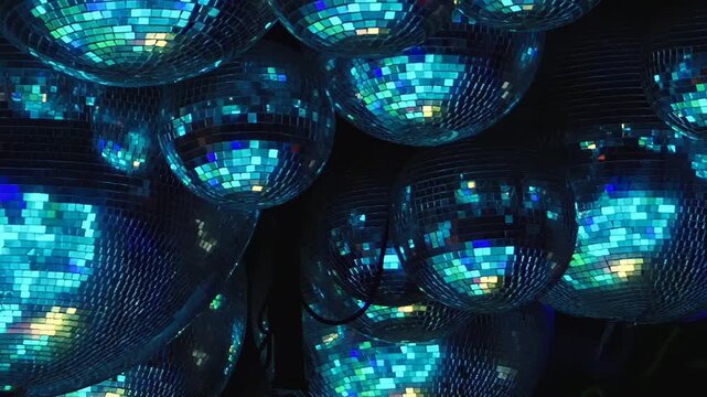 Blue and Purple Reflections Fill a Cluster of Mirror Balls. Packed reflective spheres fill the dark interior while tiled mirror surfaces scatter changing light into shimmering abstract patterns.