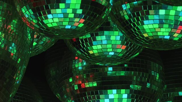 Disco Balls Scatter Multicolored Reflections in a Dark Interior. Reflective spheres fill the dark interior while tiled mirror surfaces scatter changing light into colorful abstract patterns.
