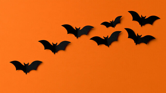Paper bats flying across a festive Halloween-themed background, playful holiday decoration concept, with copy space