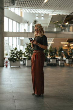 Woman messaging on smartphone in modern office building