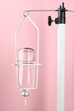 Stand with IV infusion set on pink background, closeup