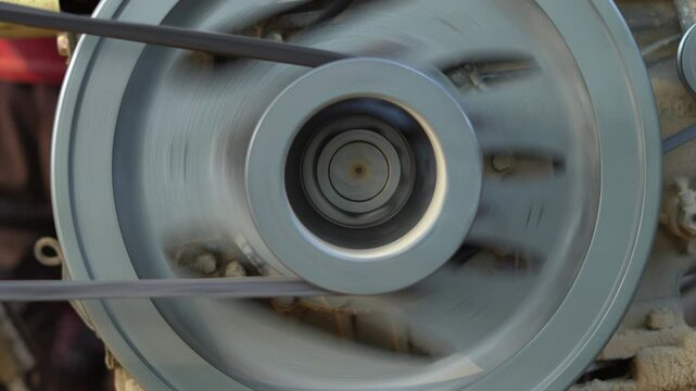 Spinning Engine Pulley Wheel and Rubber Belt Drive Transmission. Fast Rotating Metal Flywheel Pulley Wheel Transmitting Power on Industrial Machine.
